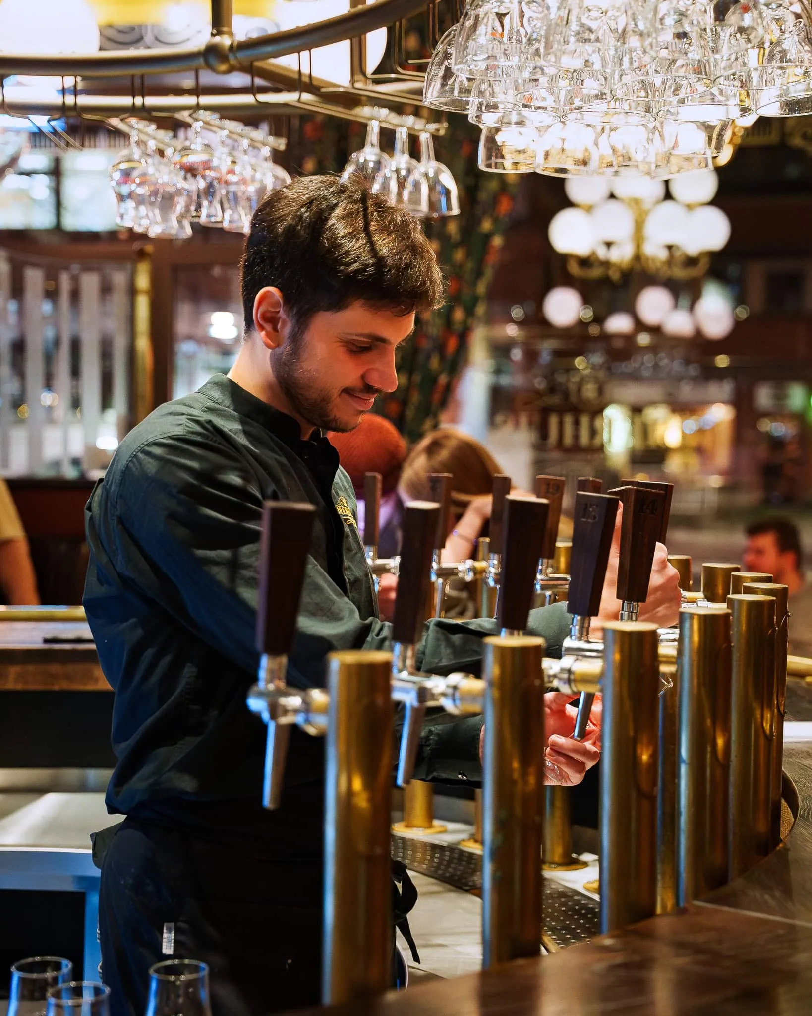 Bartender tappar belgisk fatöl vid mässingskranarna på Bierhuis i Uppsala