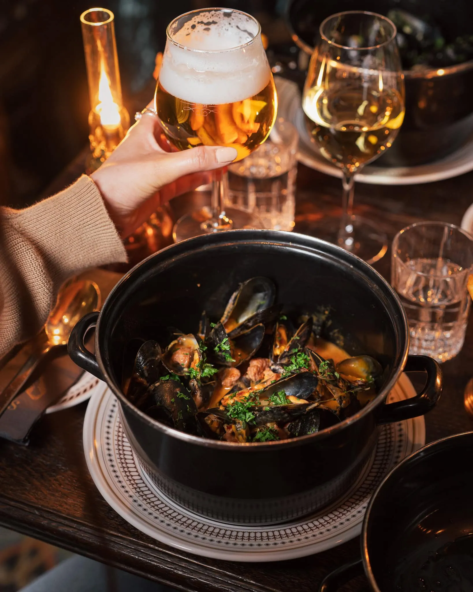 Moules frites, gryta med musslor och ett glas belgisk öl i levande ljus